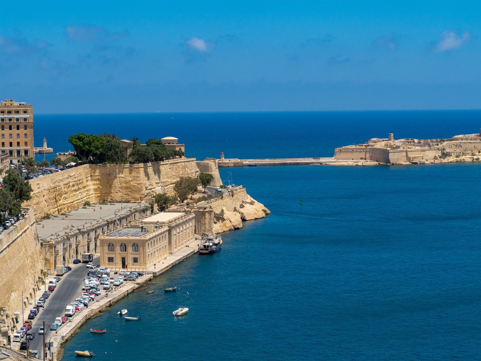 The entrance to Valletta's Grand Harbour with honey-coloured fortifications and a breakwater