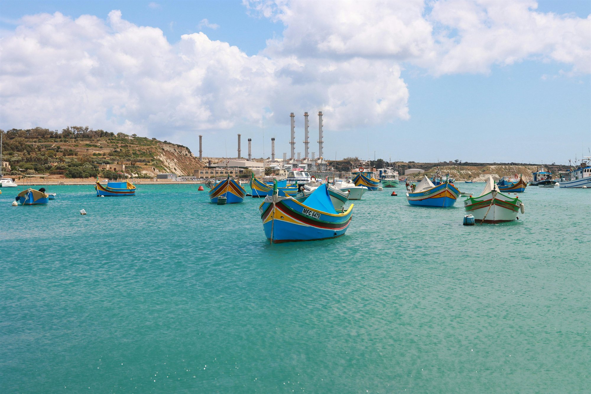 Colourful traditional luzzu fishing boats moored in the bay at Marsaxlokk, Malta